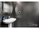 Stylish half bathroom featuring a modern round mirror and sleek pedestal sink at 12342 Carrigan Ct, Huntersville, NC 28078