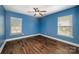 Bright bedroom features hardwood flooring, a ceiling fan, blue walls, and natural light from two windows at 124 Glade Valley Ave, Mooresville, NC 28117