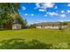 Spacious backyard with a green grass, storage shed and surrounded by trees under a partly cloudy blue sky at 189 Lochshire Ln, Woodleaf, NC 27054