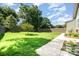 Large backyard with green grass, surrounded by a wood fence, and bordered by mature trees at 232 Orange St, Charlotte, NC 28205