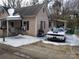 View of the home's front exterior, showcasing a covered porch and driveway with a car, all lightly dusted with snow at 2942 Reid Ave, Charlotte, NC 28208