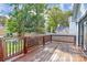 A wood deck with railing overlooks the backyard with mature trees and a seating area at 323 Keswick Ave, Charlotte, NC 28206