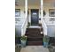 Close-up of front porch featuring a black front door and decorative plants on the wooden stairs at 323 Keswick Ave, Charlotte, NC 28206