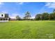 Expansive green backyard with a partial view of the residence and several trees under a clear blue sky at 3451 Greene Rd, Monroe, NC 28110