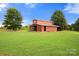 A barn set on a large grassy lawn with a clear blue sky above the tree line at 3451 Greene Rd, Monroe, NC 28110
