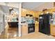 View of kitchen with black appliances and oak cabinetry adjacent to the living room at 3451 Greene Rd, Monroe, NC 28110
