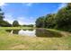 Scenic view of a tranquil pond surrounded by lush trees and green grass under a blue sky at 3451 Greene Rd, Monroe, NC 28110