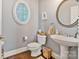 Charming powder room with pedestal sink, decorative mirror, and oval window with wooden shutters at 347 Bayberry Creek Cir, Mooresville, NC 28117