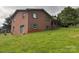 Brick home with a sliding glass door and gray shutters sits on a grassy lot with a view of mature trees at 356 Lucky Hollow Rd, Hickory, NC 28601
