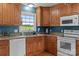 Kitchen featuring wood cabinets, granite countertops, white appliances, and a view to the outside at 522 Ne Connector Hwy, Albemarle, NC 28001