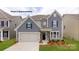 Charming two-story home with gray siding, stone accents, a two-car garage and well-manicured lawn at 7030 Butternut Oak Ter, Huntersville, NC 28078