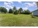 Overview of a lush, green backyard, with scattered trees and a view of the neighboring houses at 7785 Crestwood Dr, Kannapolis, NC 28081
