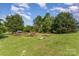 Backyard with lawn, scattered wood, and mature trees set against a blue sky with white clouds at 7785 Crestwood Dr, Kannapolis, NC 28081