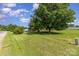Large front yard with a lush green lawn, mature shade tree, and blue sky with white clouds at 7785 Crestwood Dr, Kannapolis, NC 28081