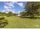 A front yard of a house with green lawn, trees, driveway, and vehicles under blue sky with white clouds at 7785 Crestwood Dr, Kannapolis, NC 28081