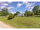 Green lawn and trees surround house with vehicles parked in driveway under a blue sky with white clouds at 7785 Crestwood Dr, Kannapolis, NC 28081