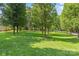 Expansive green backyard with mature trees and a view of the home in the distance at 8101 Truelight Church Rd, Mint Hill, NC 28227