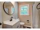 The bathroom has a round mirror, a white vanity and a black faucet at 9763 Pine Tree Ln, Norwood, NC 28128