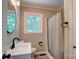 This bathroom has a round mirror above a white vanity and a shower with a curtain at 9763 Pine Tree Ln, Norwood, NC 28128