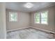 Bright bedroom features two windows, light gray walls, gray trim and gray vinyl flooring at 9763 Pine Tree Ln, Norwood, NC 28128