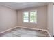 Bright bedroom features two windows, light gray walls, gray trim and gray vinyl flooring at 9763 Pine Tree Ln, Norwood, NC 28128