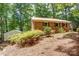 Charming brick home surrounded by lush greenery, with a metal roof and well-maintained landscaping at 9763 Pine Tree Ln, Norwood, NC 28128