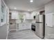 This kitchen offers white cabinets, stainless steel appliances, and gray wood look floors at 9763 Pine Tree Ln, Norwood, NC 28128