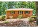 Well-maintained single-story brick home with black shutters and metal roof amidst green landscaping at 9763 Pine Tree Ln, Norwood, NC 28128