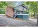 View of the brick home's rear with a covered porch, surrounded by lush trees and landscaping at 9763 Pine Tree Ln, Norwood, NC 28128