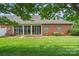 Back of the brick house featuring a screened in porch and green yard at 104 Mooreland Ne Dr, Conover, NC 28613