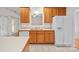 Kitchen featuring wood cabinets, white appliances, and tile flooring, with a sink and refrigerator at 104 Mooreland Ne Dr, Conover, NC 28613