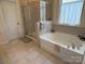 Bright bathroom featuring a soaking tub, a glass enclosed shower, and neutral tile flooring at 10417 Bluejack Oak Ct, Huntersville, NC 28078