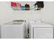 Bright laundry room with white washer and dryer, plus storage shelf and organized cleaning and laundry supplies at 1101 Plaza Walk Dr, Charlotte, NC 28215