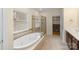 Bright bathroom featuring a soaking tub, glass-enclosed shower, and tile flooring at 1119 Williamstown Rd, Matthews, NC 28105