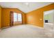 Bedroom with large windows, neutral carpet, and an orange accent wall at 11608 Downy Birch Rd, Charlotte, NC 28227