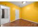 Empty room with yellow walls and hardwood floors and view into another room at 11608 Downy Birch Rd, Charlotte, NC 28227
