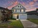 Charming two-story home with a well-maintained lawn, driveway, and attached garage, situated under a colorful twilight sky at 12131 Honor Guard Ave, Charlotte, NC 28277