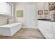 Elegant bathroom featuring a soaking tub, white cabinetry, and wood-look tile flooring at 141 Castle Dr, Mooresville, NC 28117