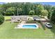An aerial view shows a pool and covered parking, all surrounded by green grass at 1489 L R Schronce Ln, Iron Station, NC 28080