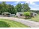 Gravel driveway leading to a carport and manufactured home with a landscaped front yard at 1489 L R Schronce Ln, Iron Station, NC 28080