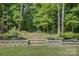 The backyard features a stone retaining wall, landscaped garden beds, and a fire pit in a wooded setting at 17537 Caddy Ct, Charlotte, NC 28278