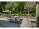 Spacious patio with dining set, built-in grill, and pergola, surrounded by lush landscaping and trees at 17537 Caddy Ct, Charlotte, NC 28278