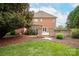 Brick home showcasing a spacious backyard with lush lawn, mature trees, and access to a stone patio area at 2019 Heirloom Ct, Matthews, NC 28104