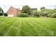 Expansive backyard with lush green grass, mature trees, and a charming fence at 2019 Heirloom Ct, Matthews, NC 28104