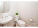 Cozy powder room featuring a modern sink, toilet, and decorative mirror at 2019 Heirloom Ct, Matthews, NC 28104