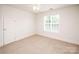 Well-lit bedroom with a window, soft carpet, and a classic white door at 2019 Heirloom Ct, Matthews, NC 28104