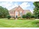 Stately brick home featuring a manicured lawn, mature trees, and meticulously shaped shrubs for enhanced curb appeal at 2019 Heirloom Ct, Matthews, NC 28104
