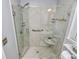 Bathroom shower with marble-style tile, glass surround, and built-in shelving at 3304 Chilham Pl, Charlotte, NC 28226