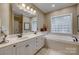 Bathroom with a double vanity, large mirror, soaking tub, and a glass block window at 413 Farm Branch Dr, Fort Mill, SC 29715