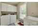 Bright laundry room with white cabinets, modern washer/dryer, and a large sink under a window at 413 Farm Branch Dr, Fort Mill, SC 29715